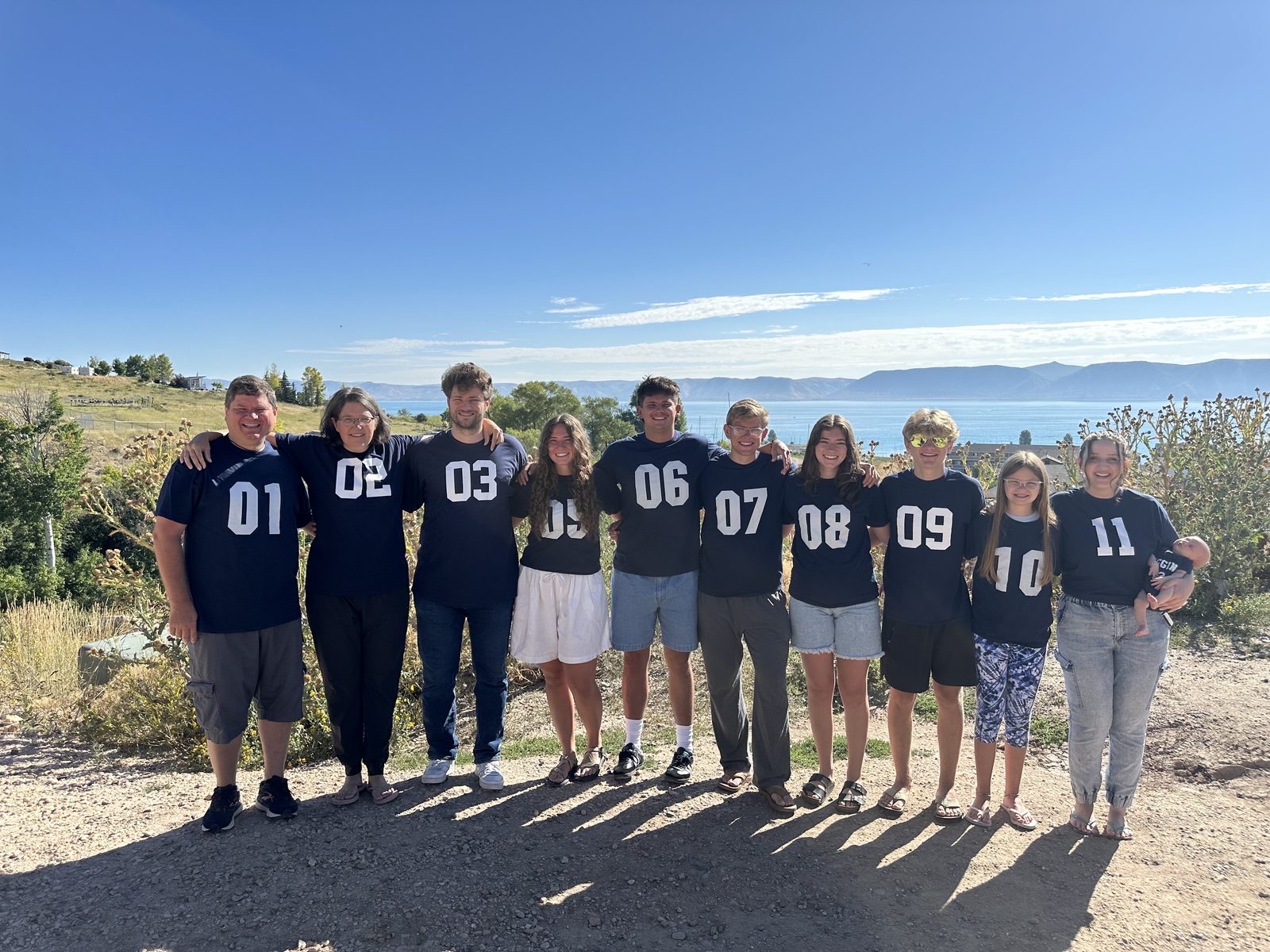 The whole family outdoors at a mountain lake wearing numbered jerseys